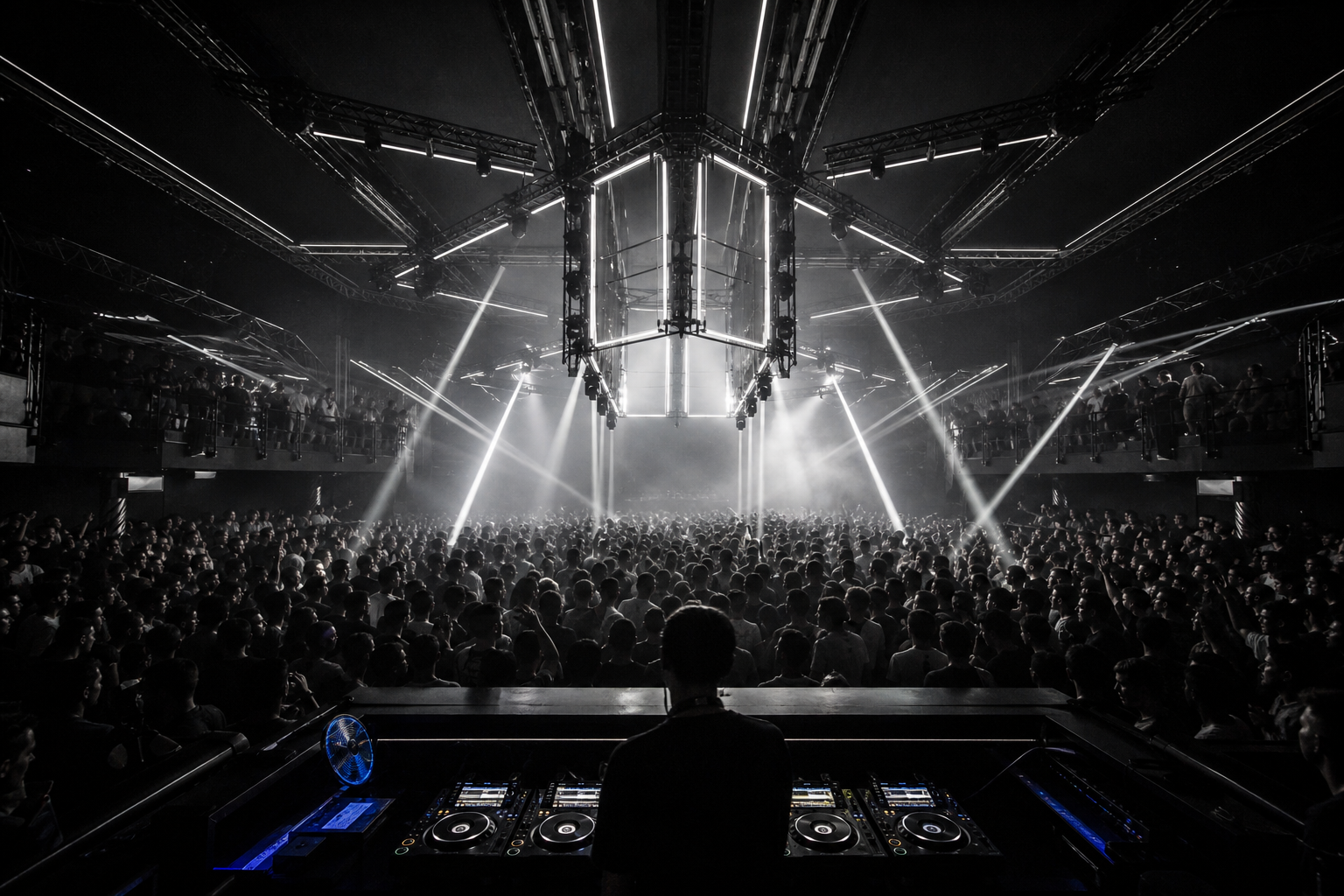 A full nightclub dancefloor beneath a geometric white lighting installation